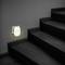 A night light illuminates the wall beside a staircase in a dark room.