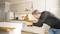 A man is repairing a drawer with a screwdriver in a modern kitchen. He is wearing glasses and is focused on his work.