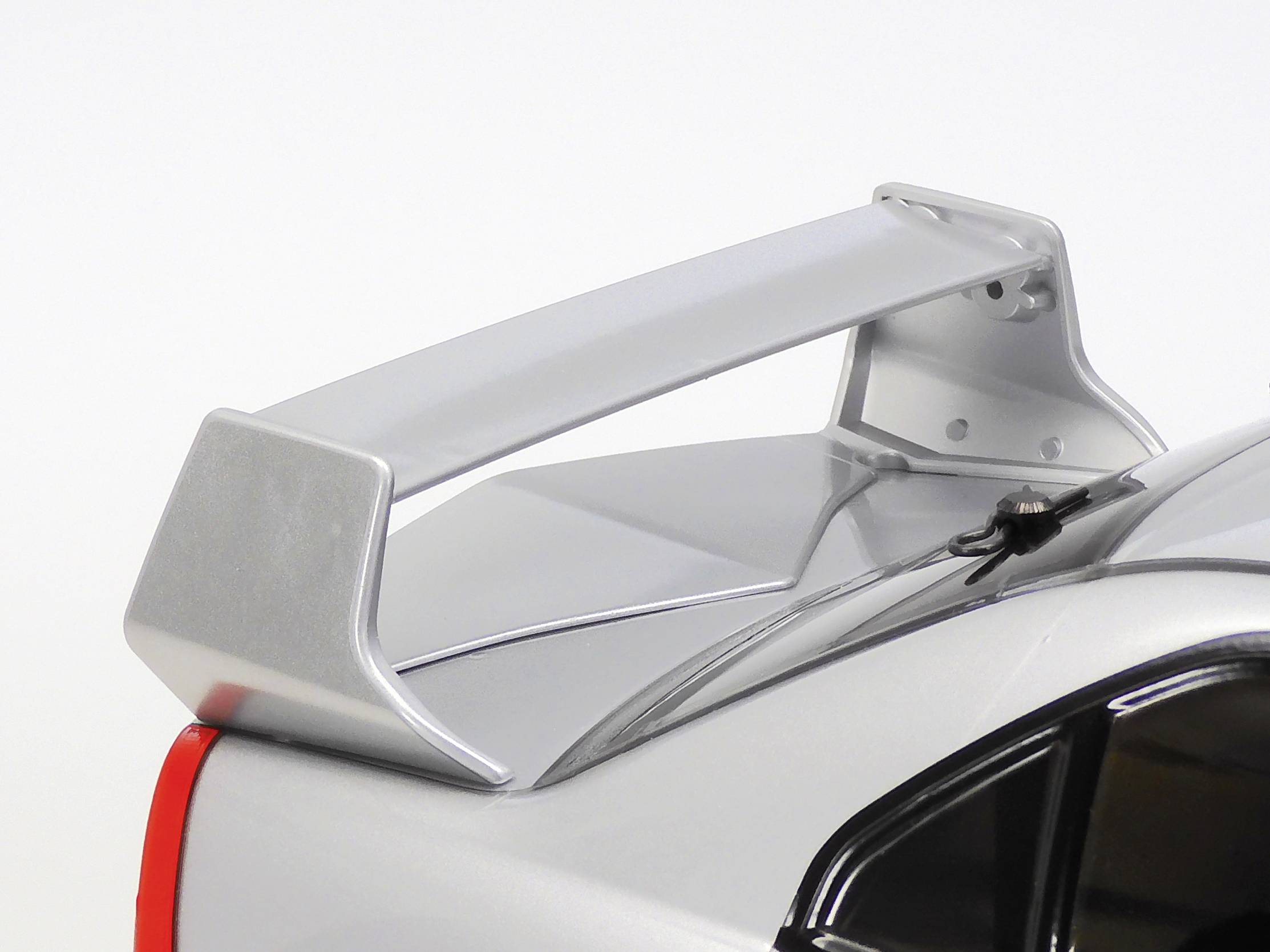 A silver sports car with a large rear spoiler. The image focuses on the aerodynamic rear section of the vehicle.