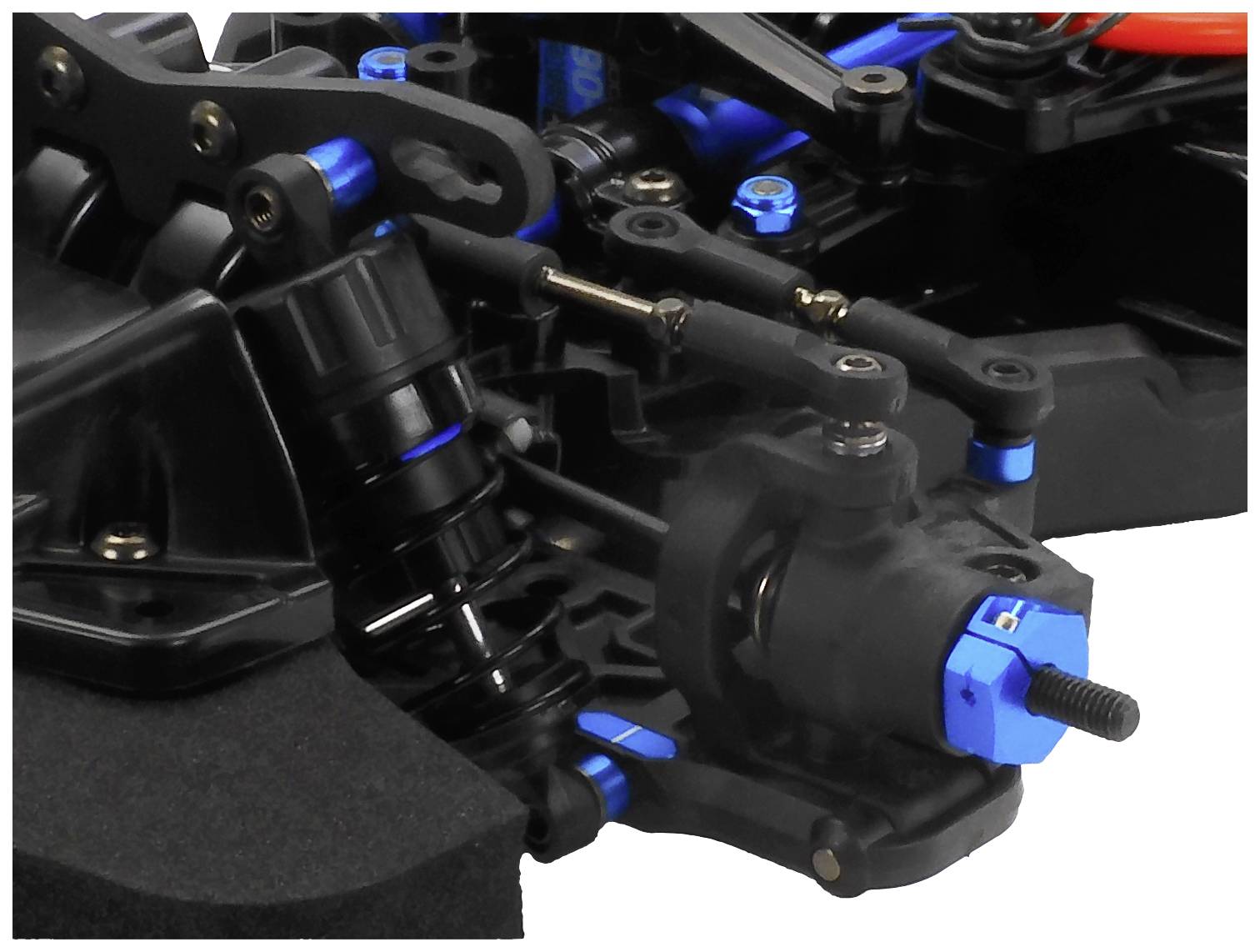 Close-up of a remote-controlled car part, showing the suspension and blue aluminium components.