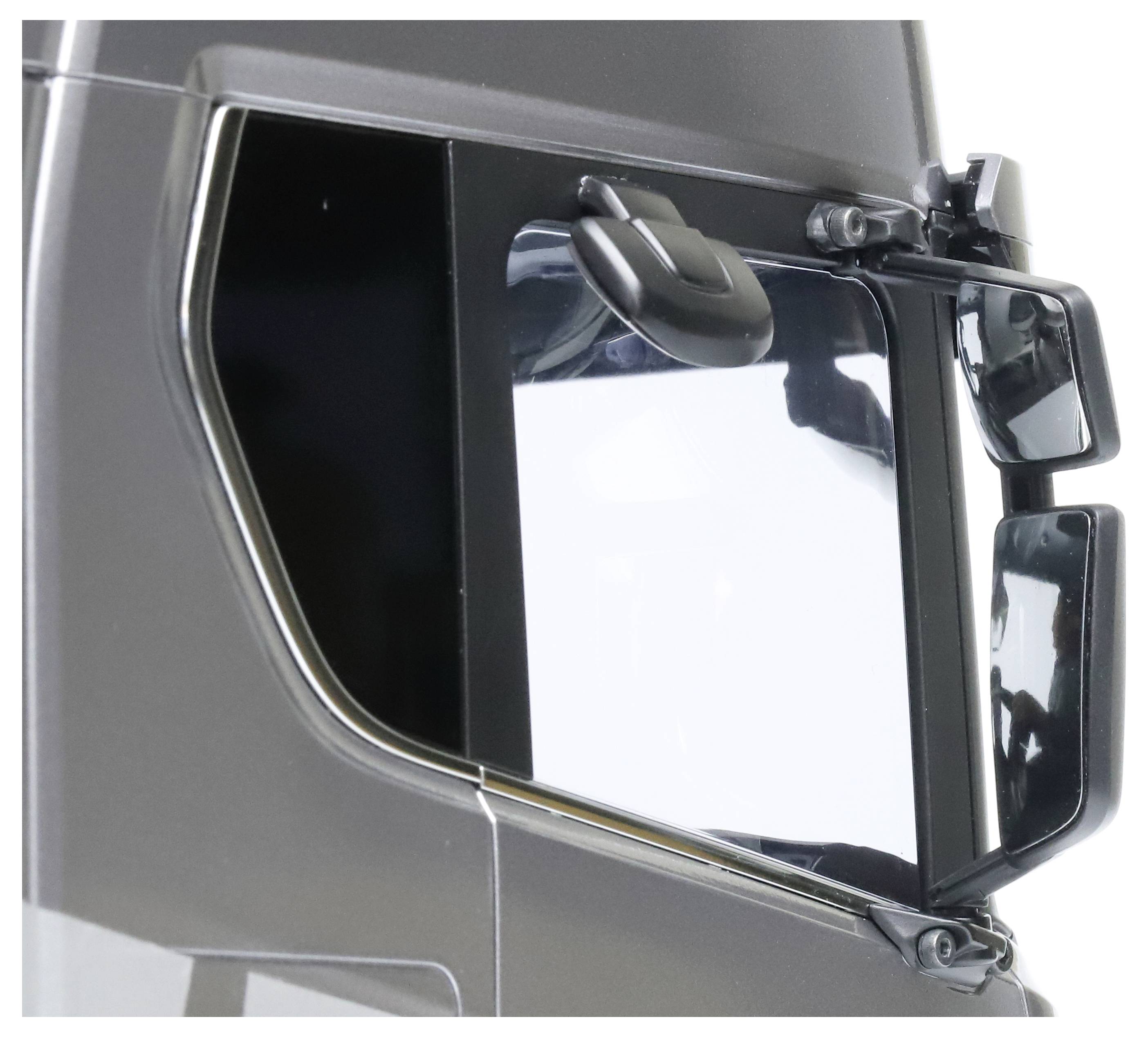 Close-up of a lorry wing mirror against a grey wall. The mirror reflects a clear sky, suggesting fine weather.