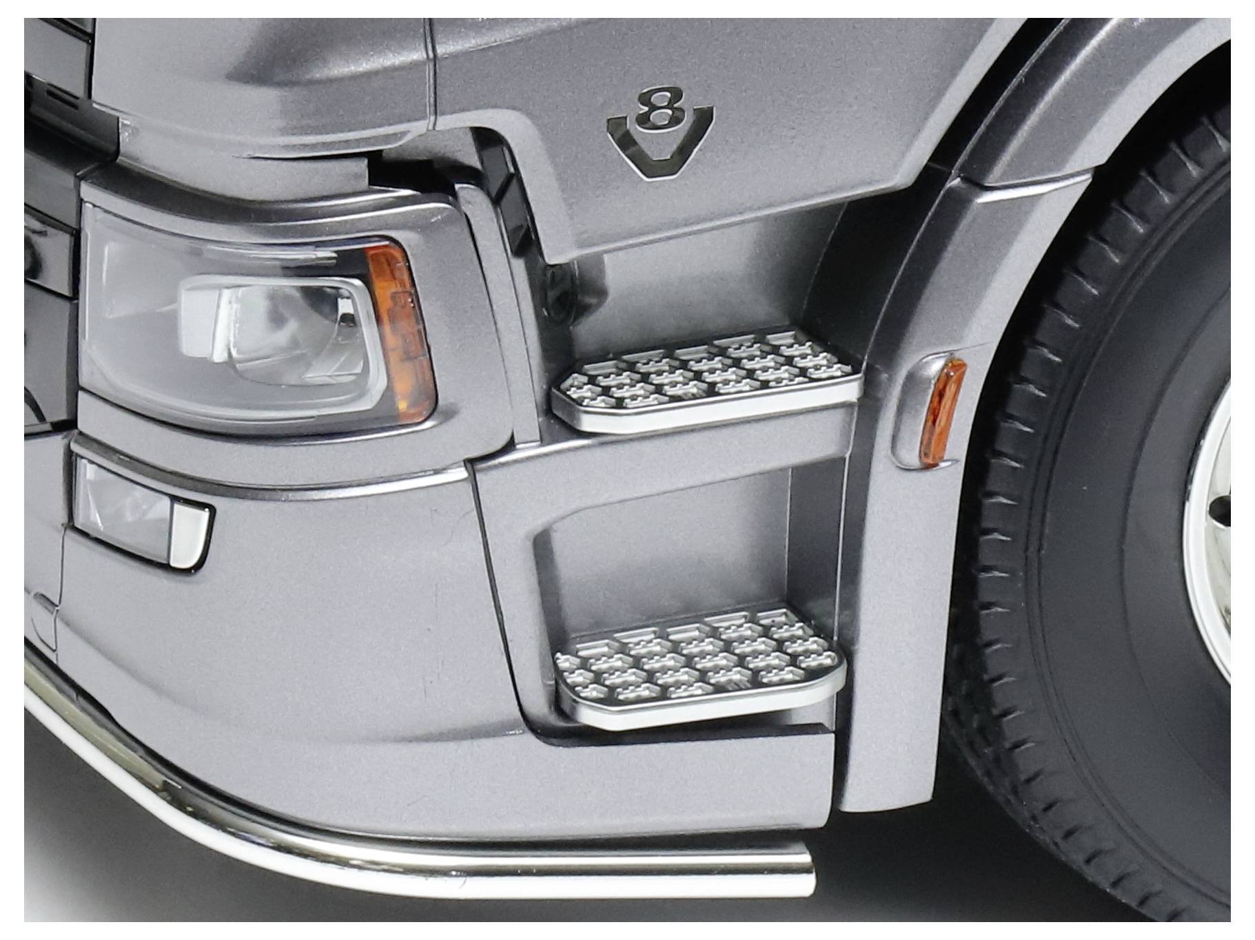 Close-up of the V8 badge and running boards of a silver vehicle.