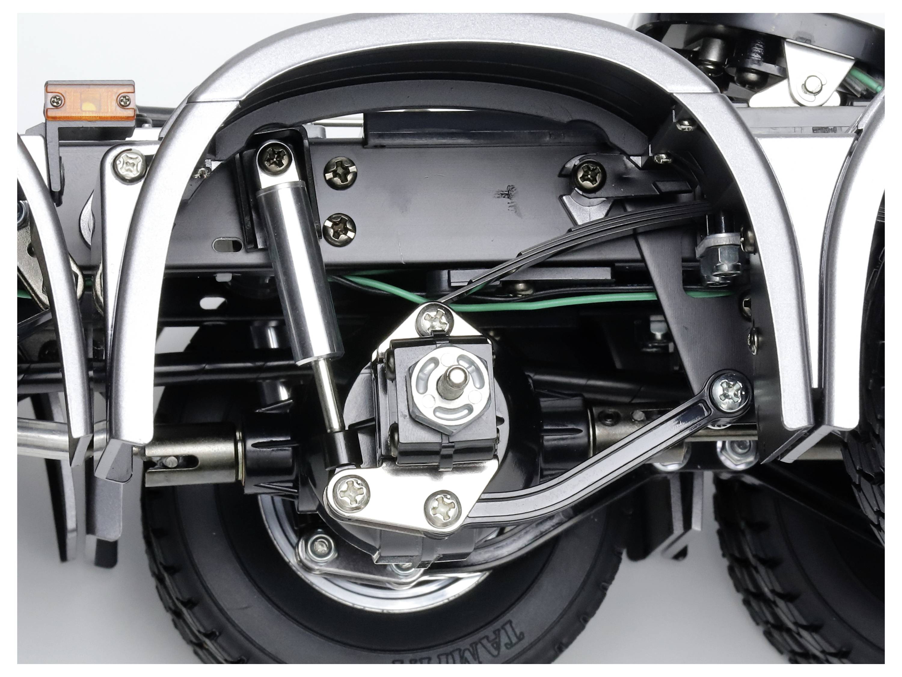 Close-up of a complex mechanism with springs and tyres, possibly part of a vehicle or model, showing details of suspension and wiring.