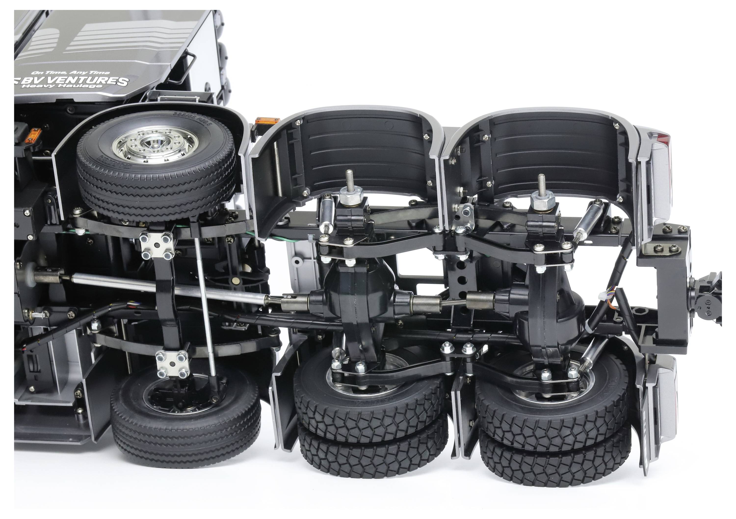 Chassis of a miniature lorry replica with six wheels and detailed suspension, showing the underside of the model.