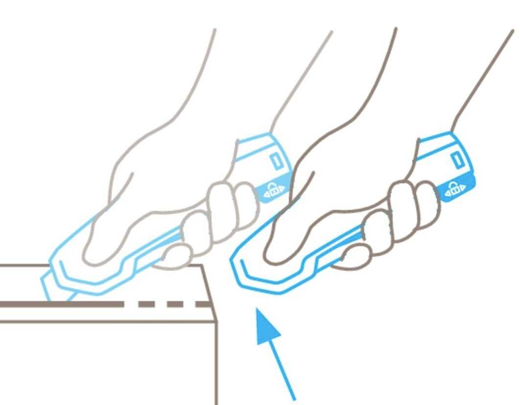 Two hands are holding safety cutters, cutting along an edge. An arrow indicates the direction of movement.