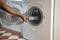 A person places a towel into an open washing machine. The interior of the drum is visible.