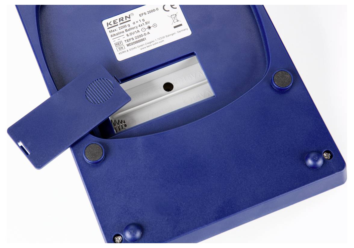 A blue electronic device, possibly a scale, with its battery compartment open. Manufacturer label reads 'Kern ETS 1000-3'.