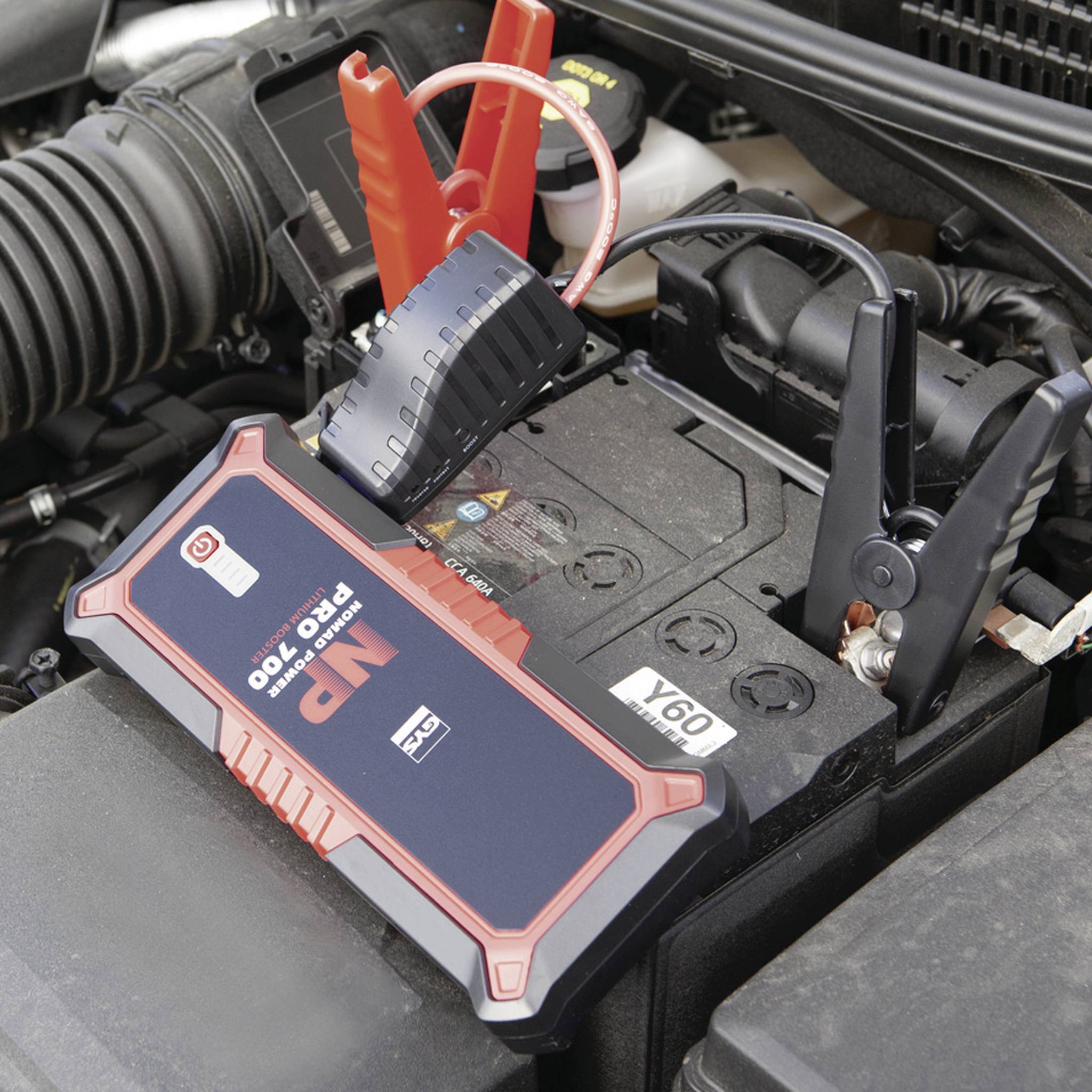 Car jump starter battery with two clamps connected to a car battery, showing the process of jump-starting to start the vehicle.