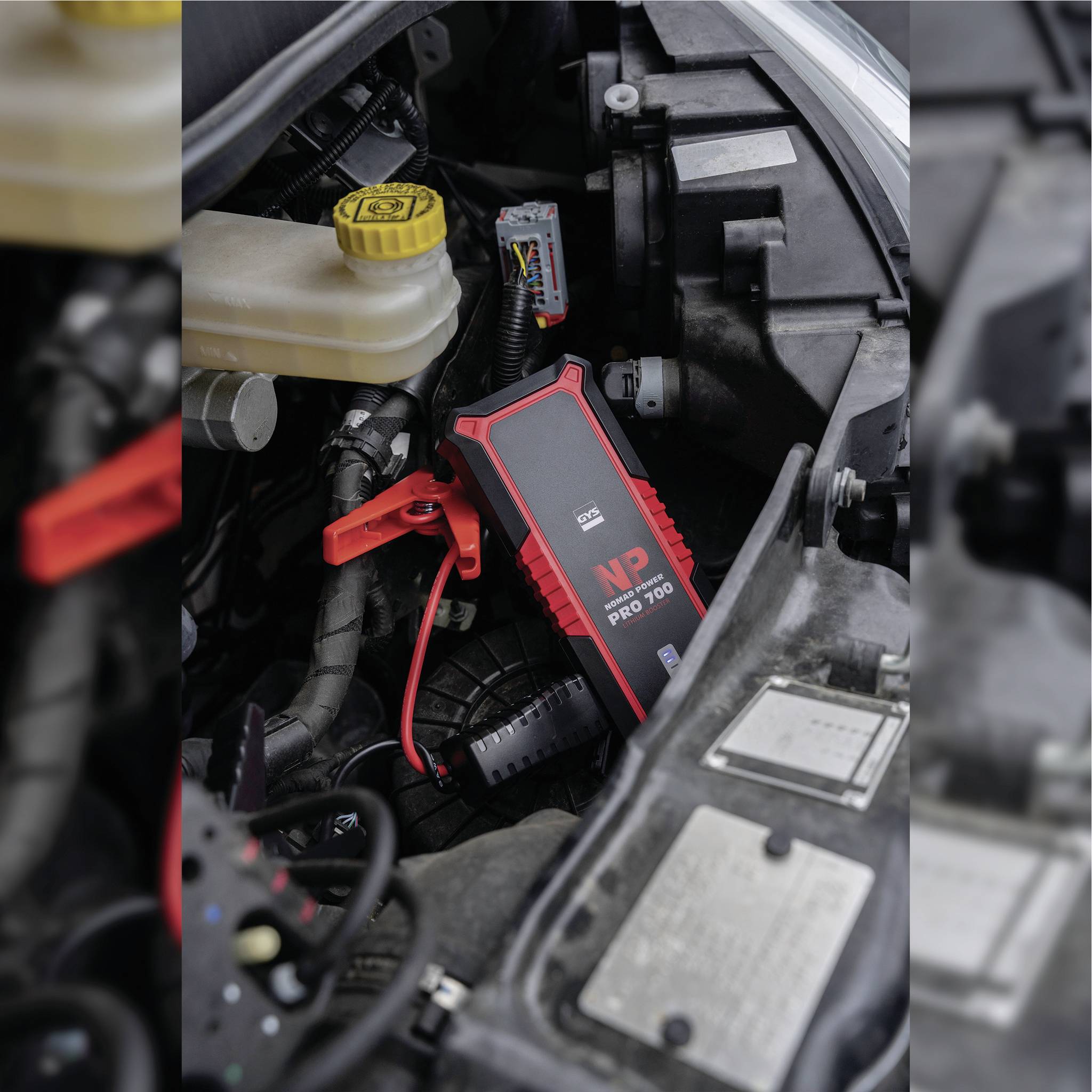 Automotive motor component with a red jump starter set connected to the battery.