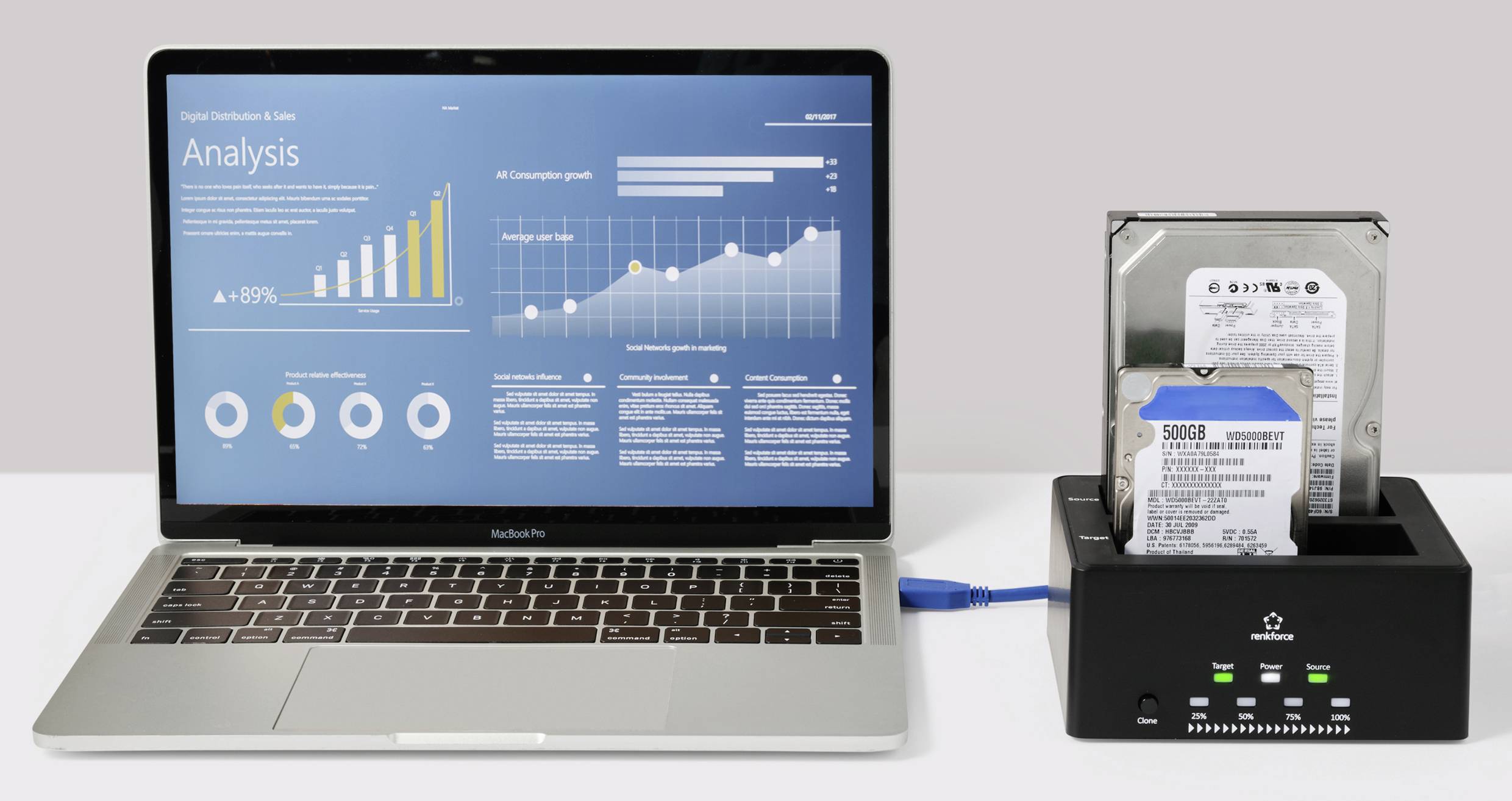 A laptop with an open analytics dashboard, displaying bar and line graphs. Next to it are two hard drives in a docking station.