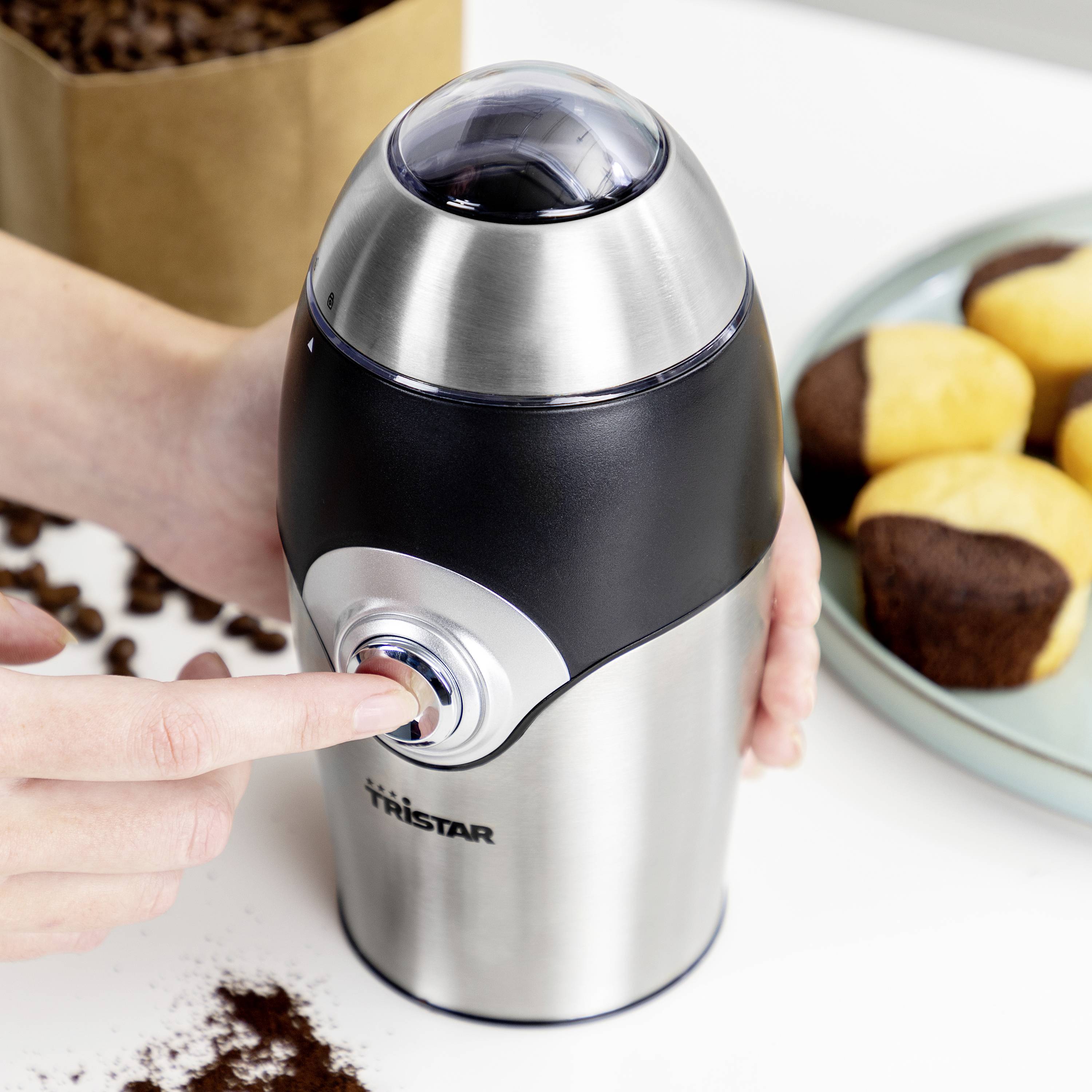 'Person operating a stainless steel coffee grinder button'