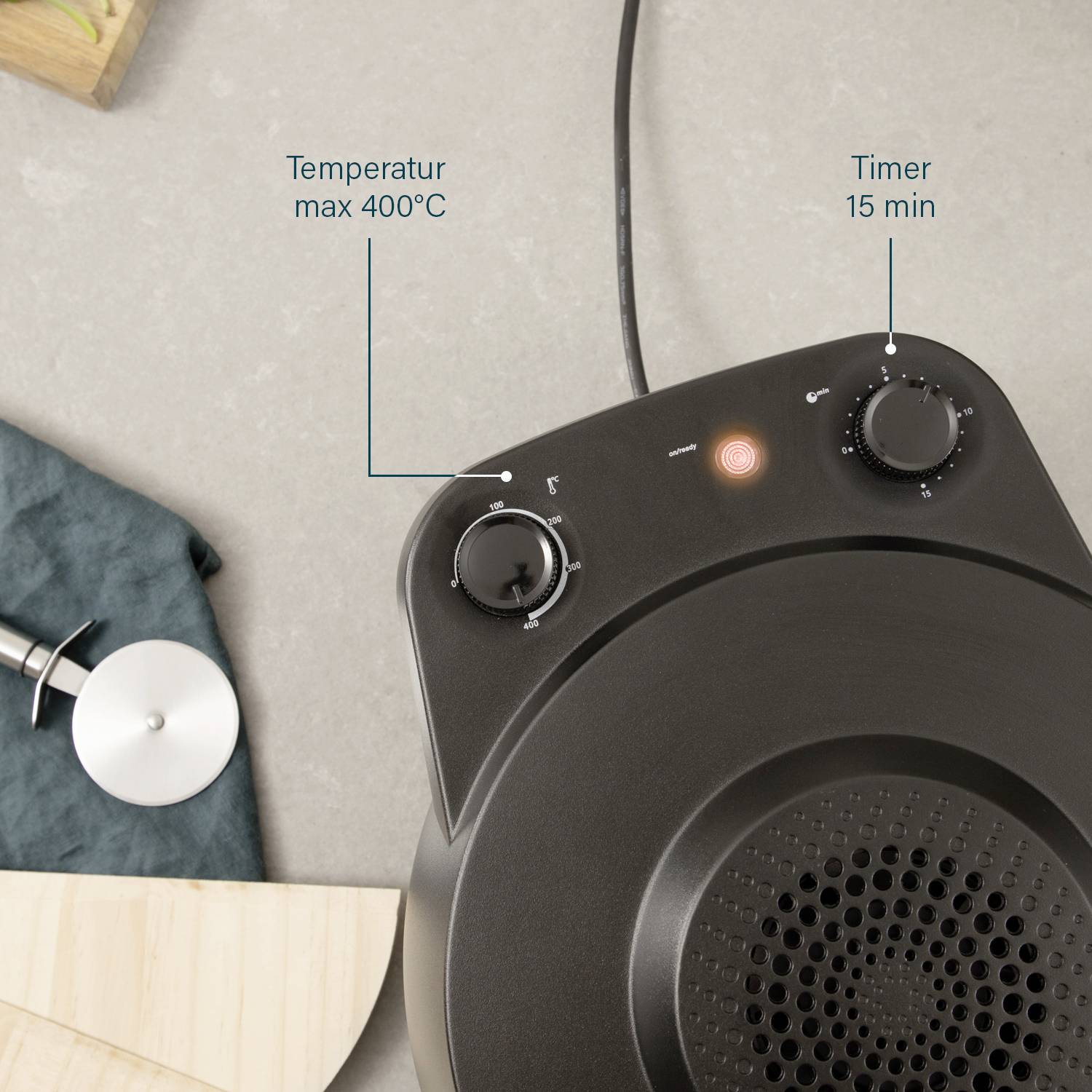 A black toaster oven with two rotary knobs on a kitchen worktop. Left knob for temperature up to 400°C, right knob for timer up to 15 minutes.