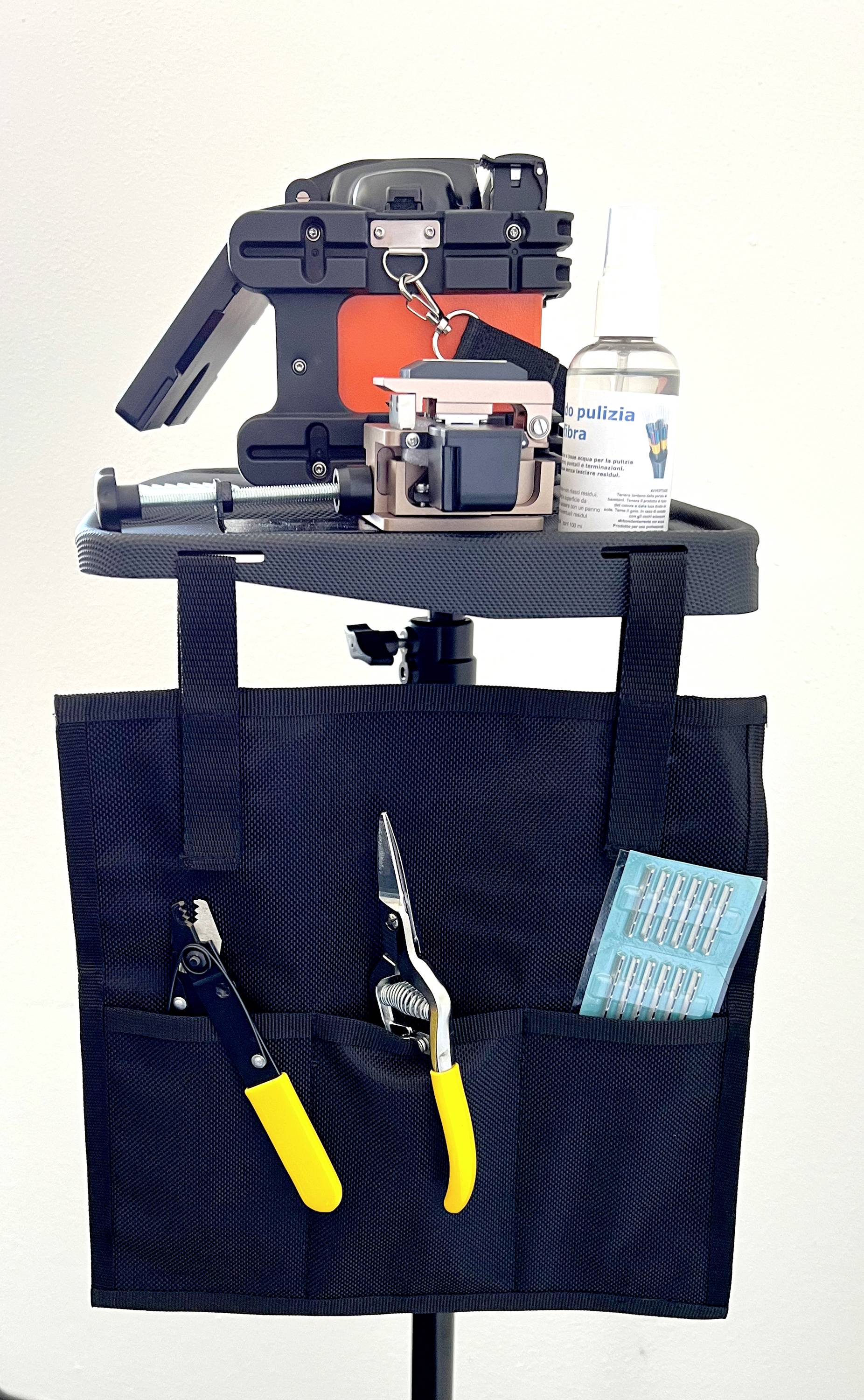 A tool holder on a stand with various tools: pliers, clamp, cleaning fluid and a drill bit set.