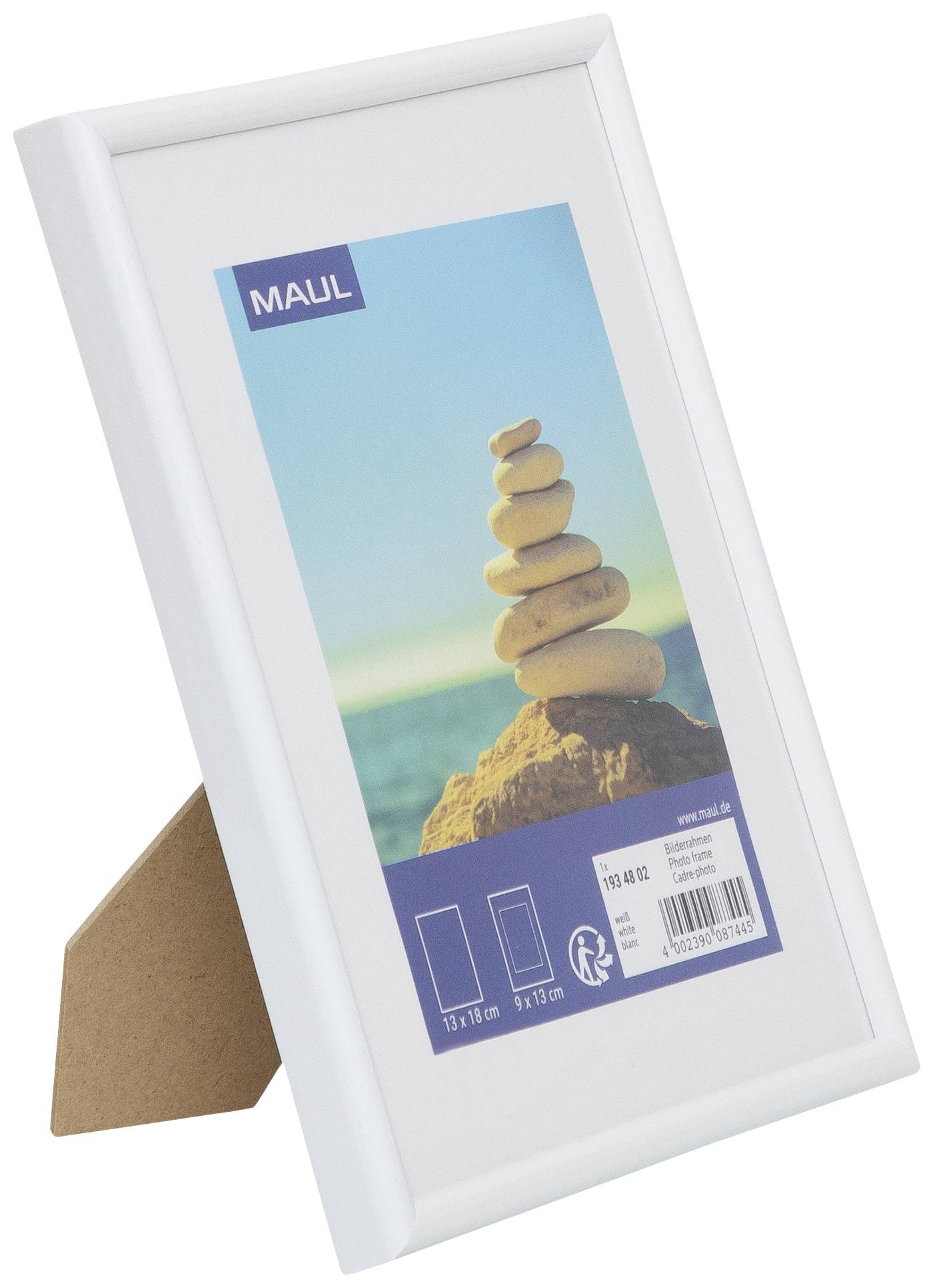 A white picture frame with a photograph of stacked stones against a blue sky and sea background. Packaging shows size 13x18 cm.