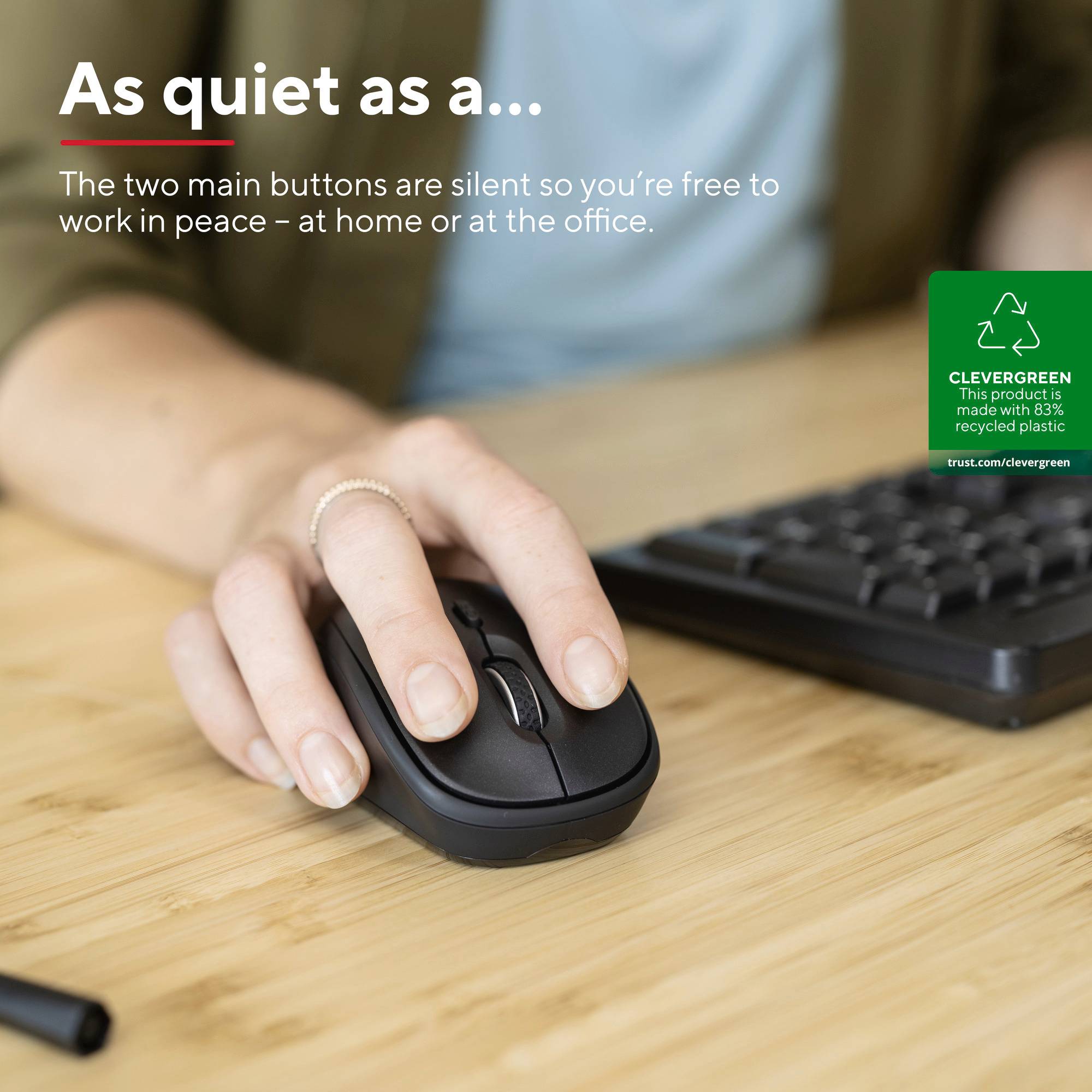 A hand is holding a silent computer mouse on a desk next to a keyboard. Text: 'As quiet as a...'.