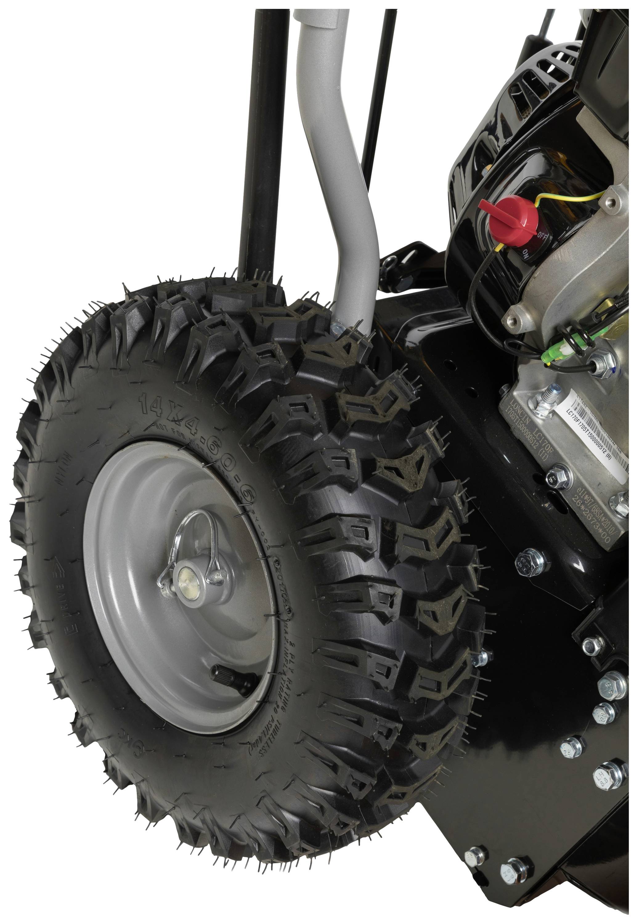 Black wheel of a machine, with a coarse tread and silver rim. Part of the engine visible in the background.