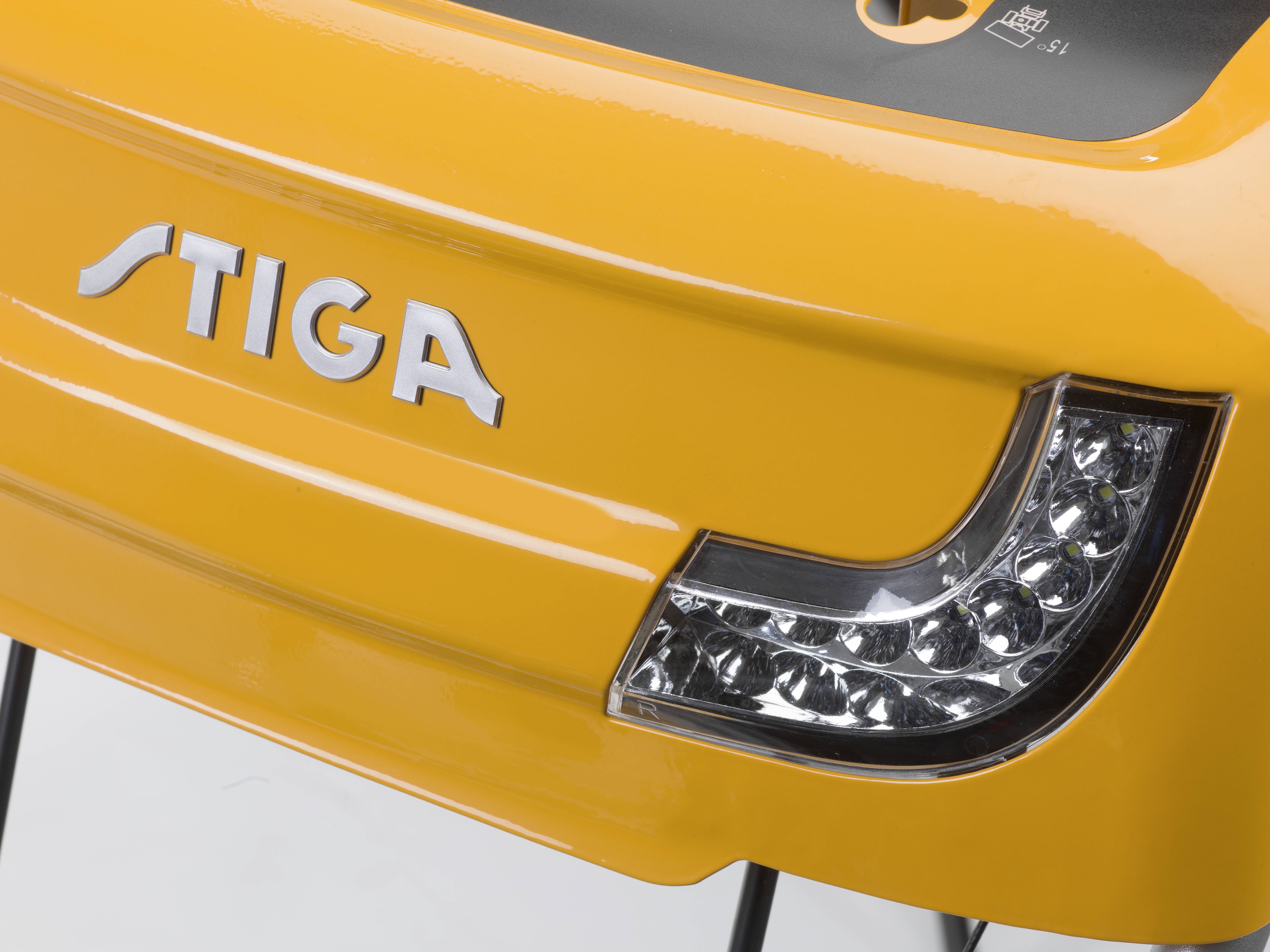 'Close-up of a yellow Stiga lawn mower switched off. Shows brand name and headlight light cover.'