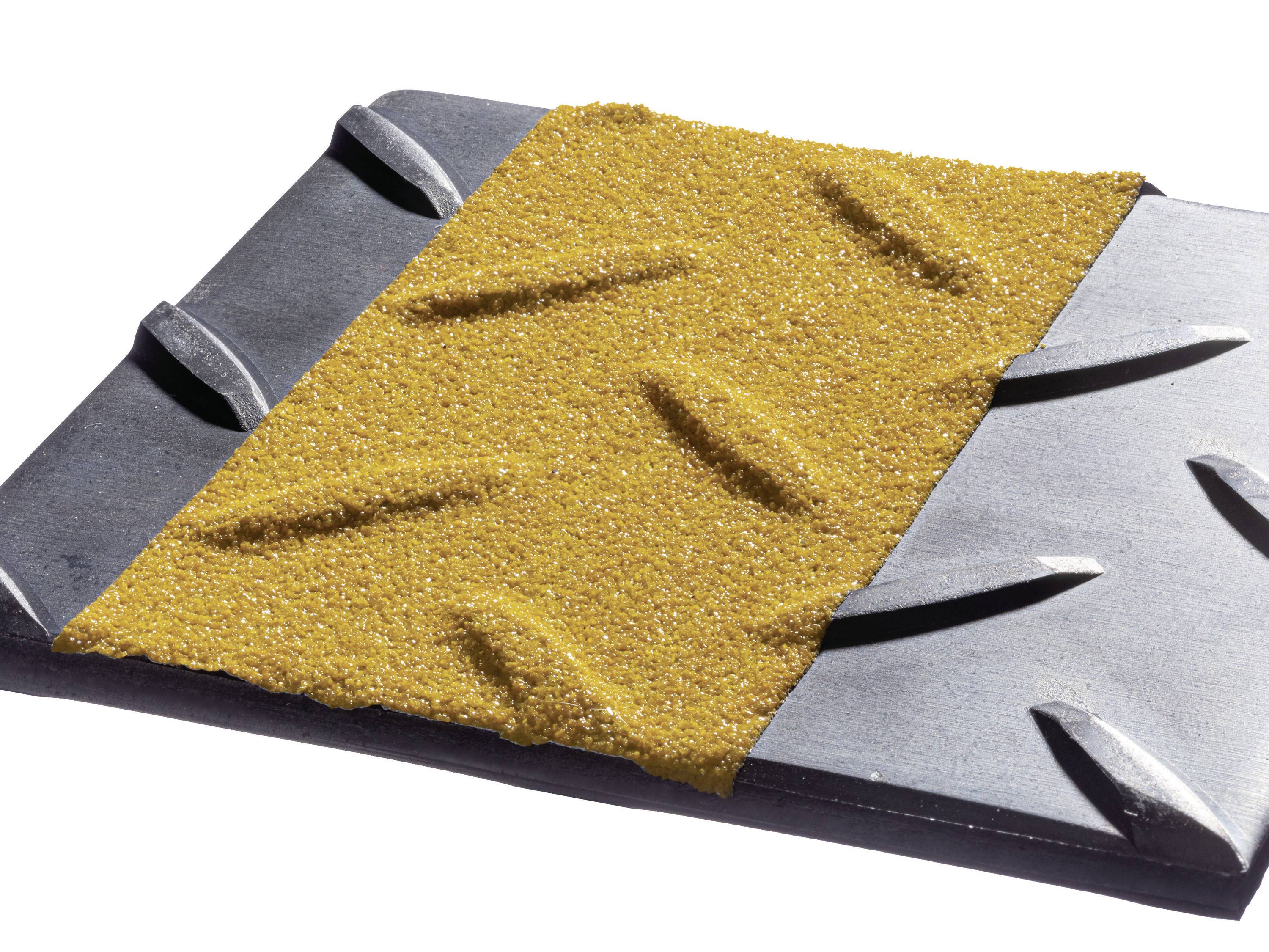 A grey metal piece with a yellow, rough sandpaper coating on the top surface, with protrusions visible on the left side.