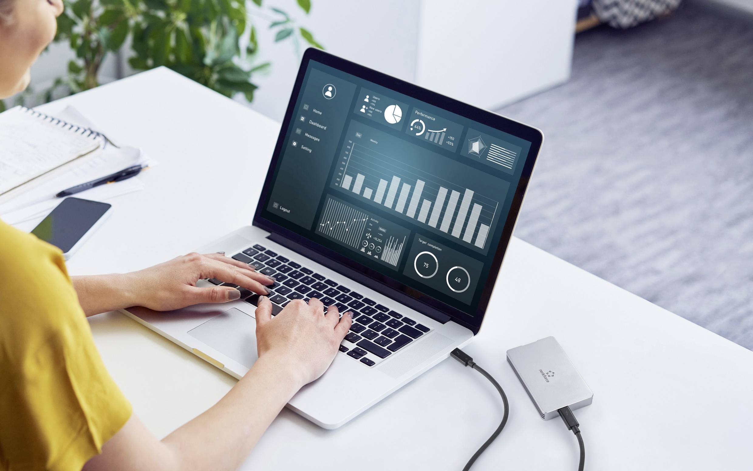 A person is working on a laptop with an open business analytics software, displaying charts and statistics.