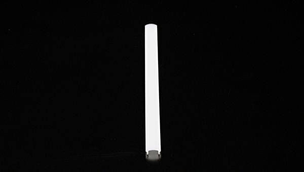 A long, narrow, white object lies on a black background.