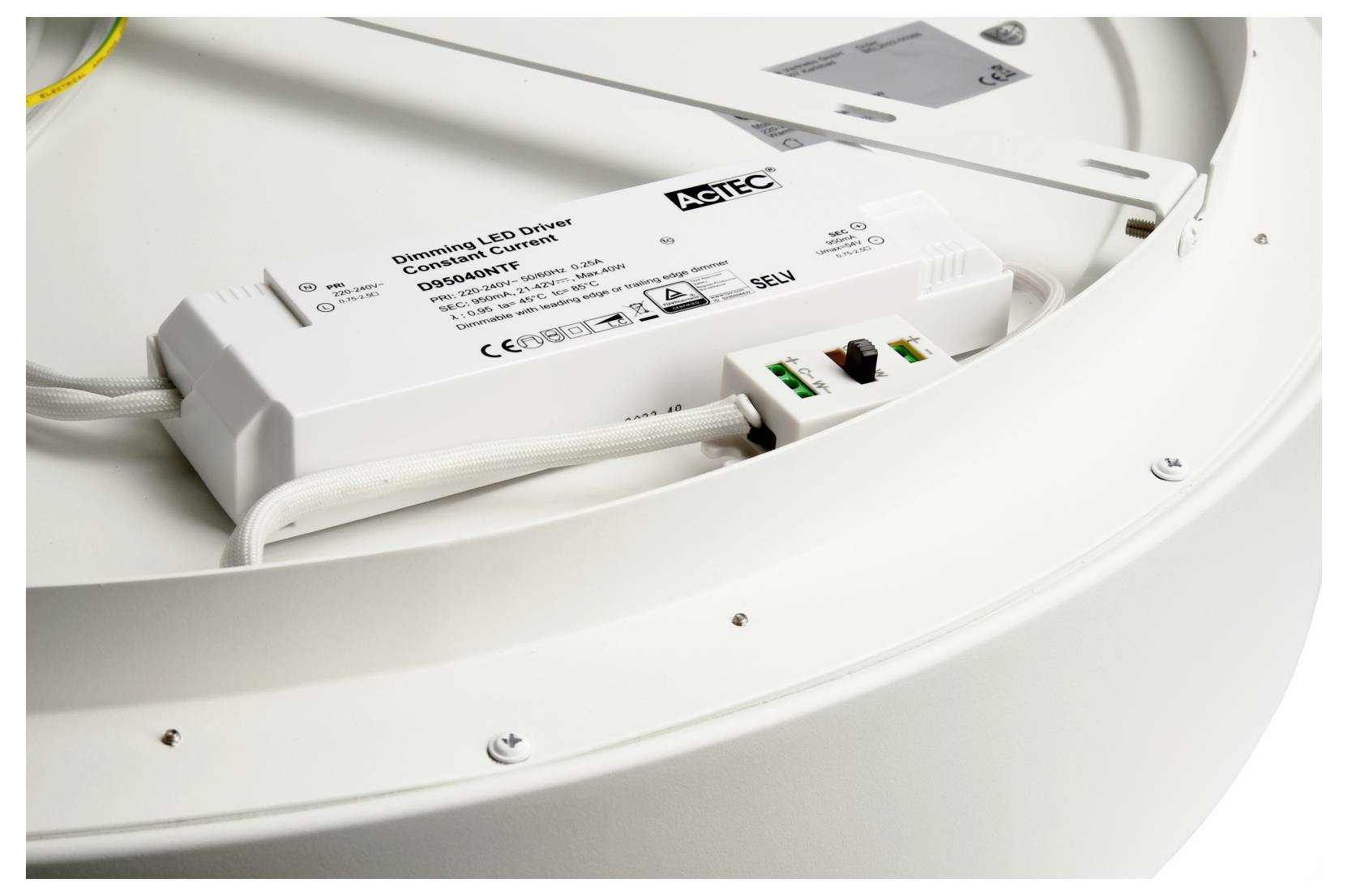LED driver and wiring installed inside a circular white light fixture, with an ACTEC control unit visible on the housing.