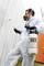 A person in a protective suit and respirator is spraying a wall with a pressure sprayer.
