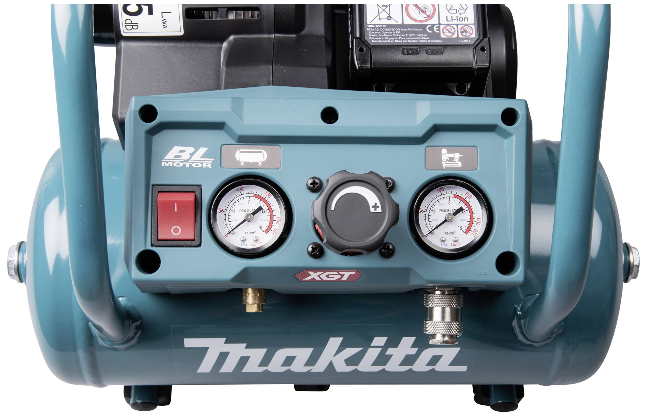 Close-up of a turquoise Makita compressor with pressure gauges and switches on the front.