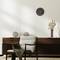 Bright room with a wooden sideboard, decorated with modern globe lamps, a vase with branches, and a wall clock.