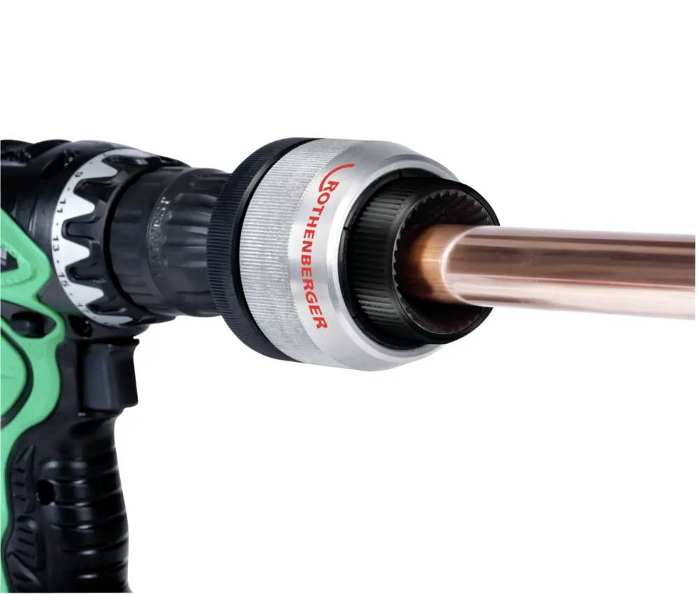 Power drill fitted with a Rothenberger pipe cutter, cutting a copper pipe, demonstrating a tool for plumbing or construction tasks.