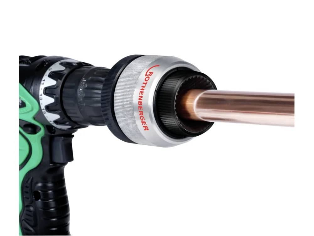 A drill fitted with a Rothenberger cutting tool is shown cutting a copper pipe.