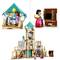 Building toy set with figures in a detailed house. One figure is holding a bowl, another is standing in a living area.