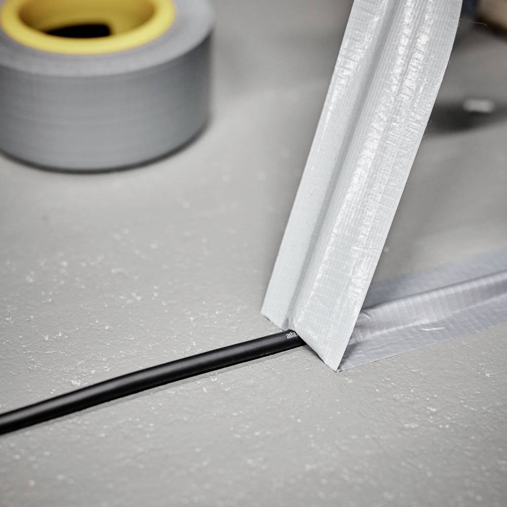 An electrical cable is secured to the floor with grey gaffer tape to ensure safety and prevent trip hazards.