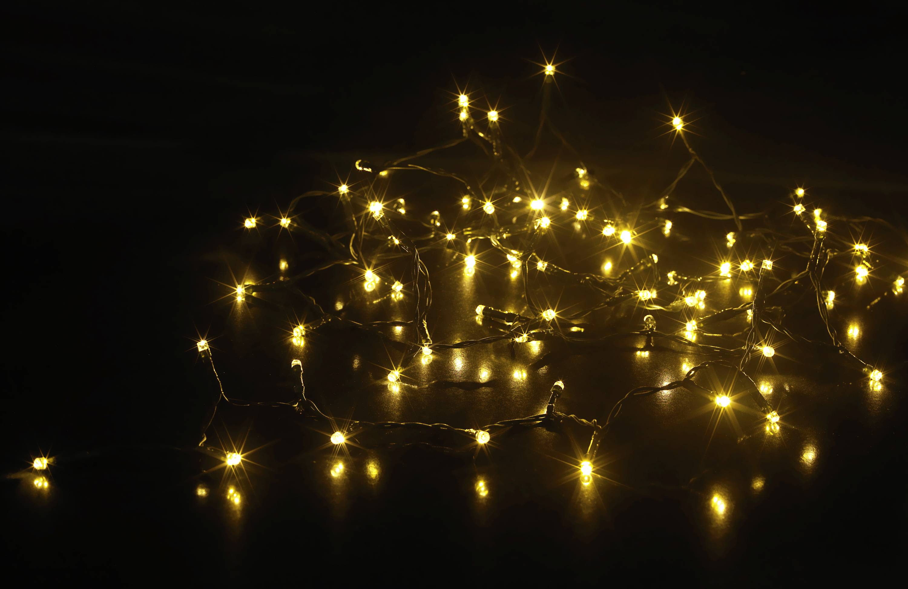 A string of fairy lights with warm yellow light lies on a dark background, creating a mood-enhancing and festive atmosphere.