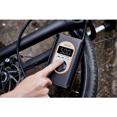 A person is inflating a bicycle tyre using a digital compressor. The compressor displays '5000' on the screen.
