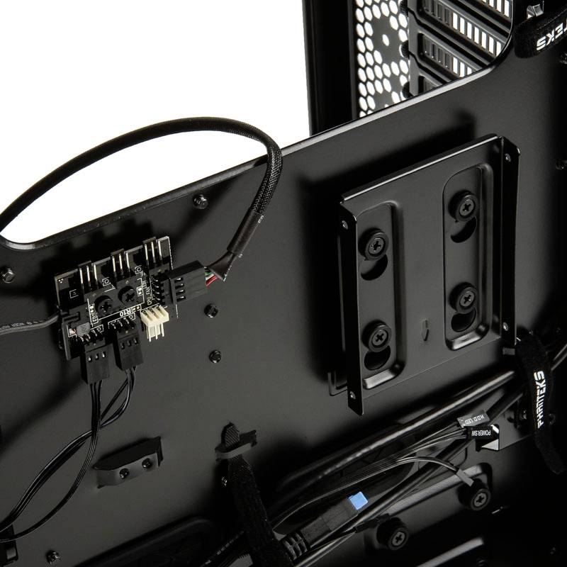 Interior of a computer chassis with cables and a small circuit board. On the left, cable connections, and on the right, mounting rails for hard drives.