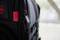 A black rucksack with red accents and an open zip revealing the upper section. Only part of the rucksack is visible.