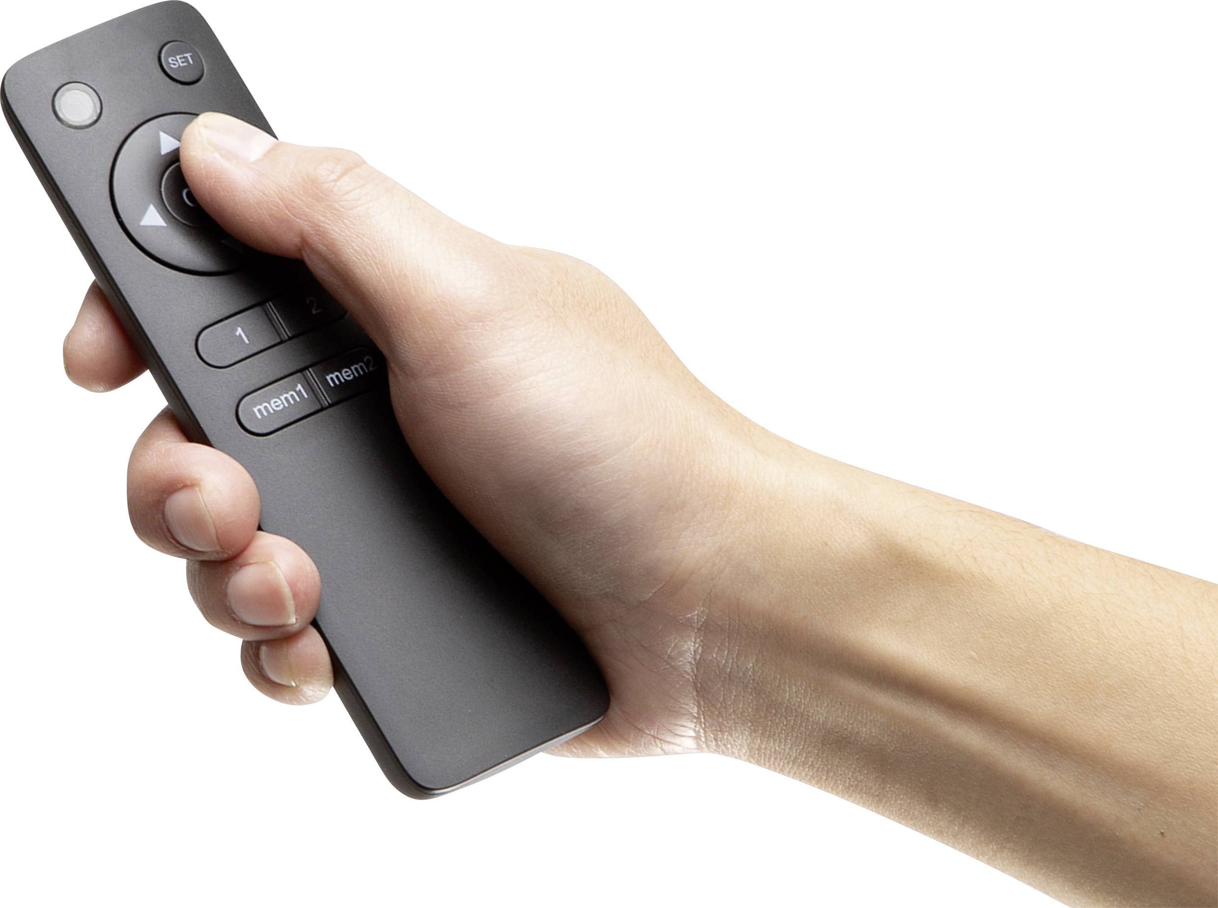 A hand is holding a black remote control, poised to press the central button.