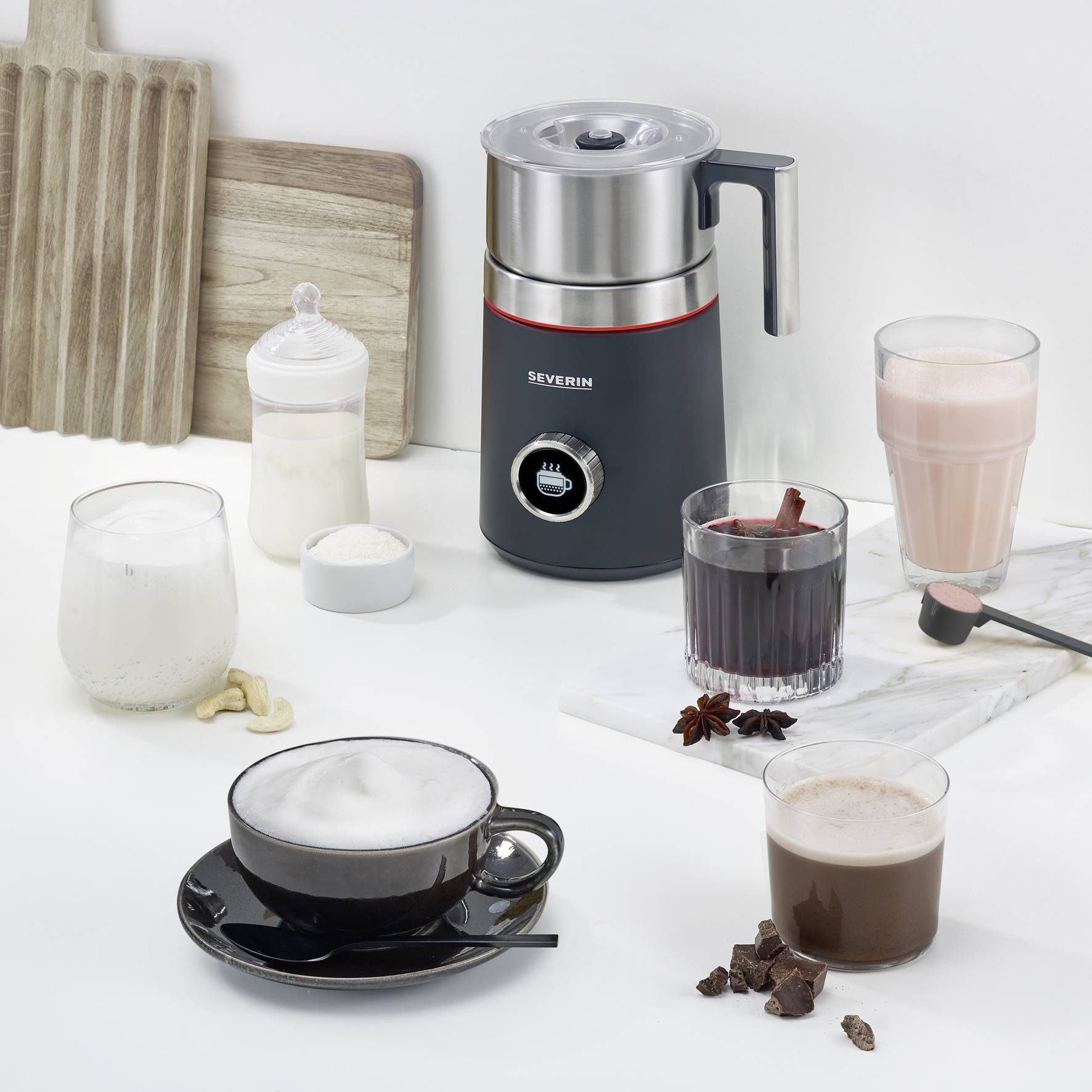 A table with a milk frother, surrounded by various beverages such as smoothies, coffee, hot chocolate, and yoghurts.