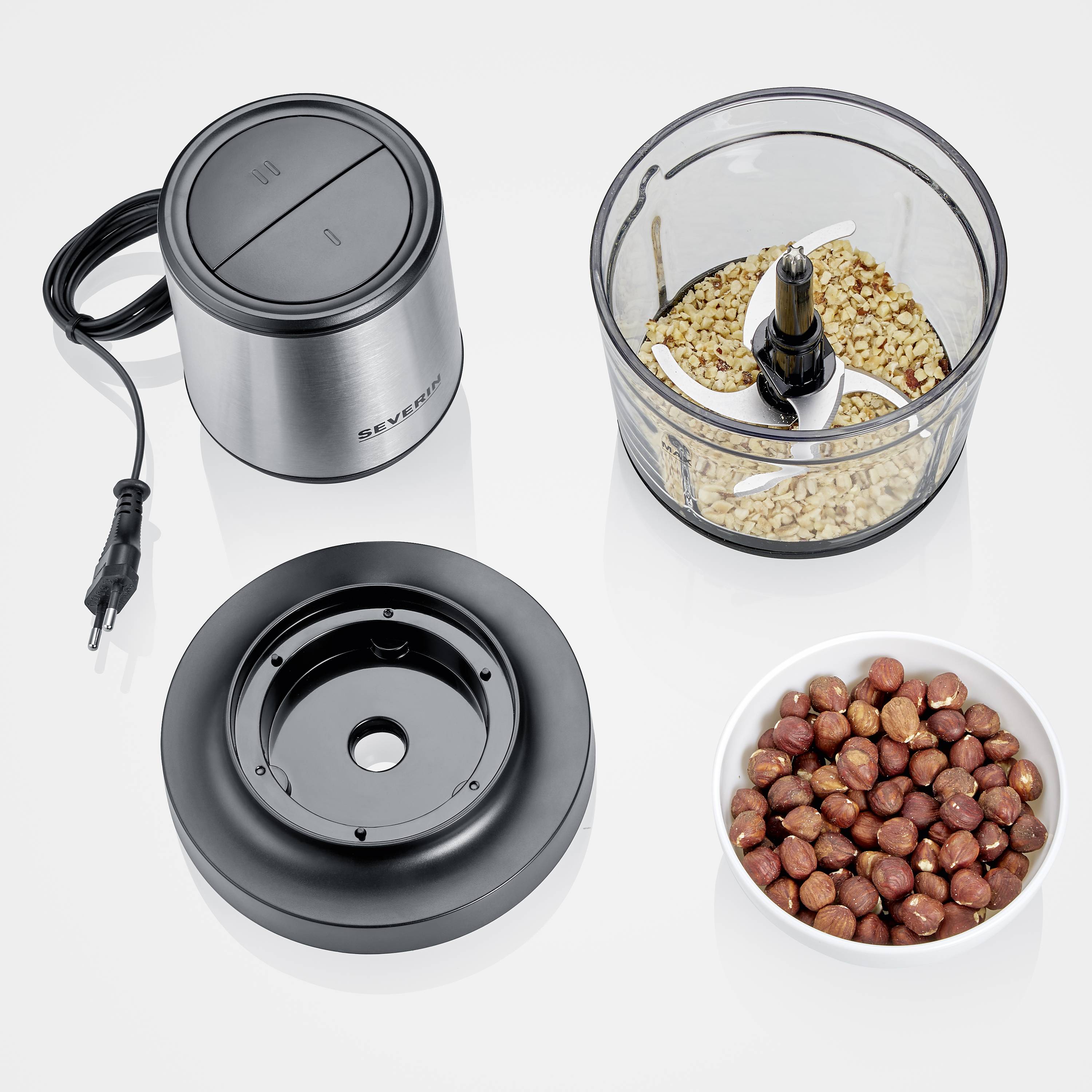 Electric chopper, consisting of motor block, cutting mechanism, bowl with chopped nuts, and bowl with whole hazelnuts.