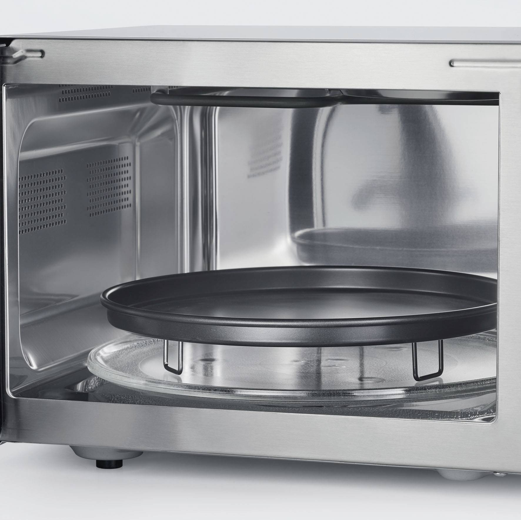 A microwave oven with its door open reveals its interior, showing the turntable and metal lining.