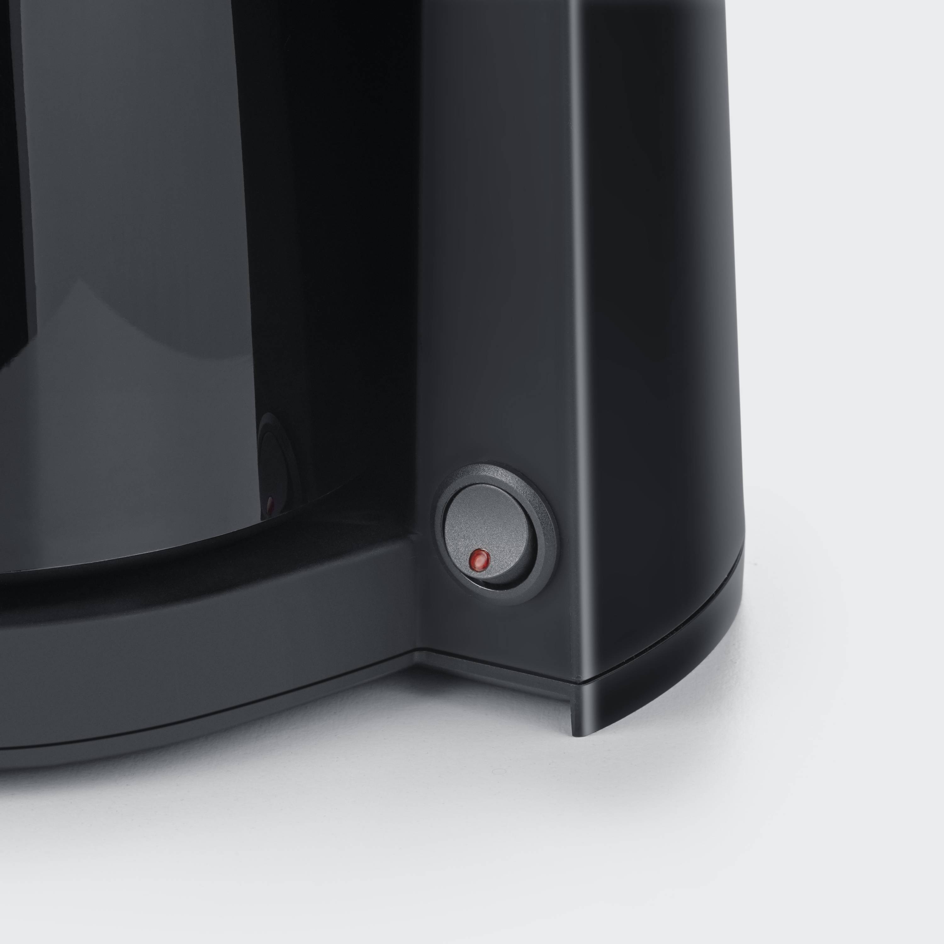 A close-up of a black kettle with a red power switch at its base.