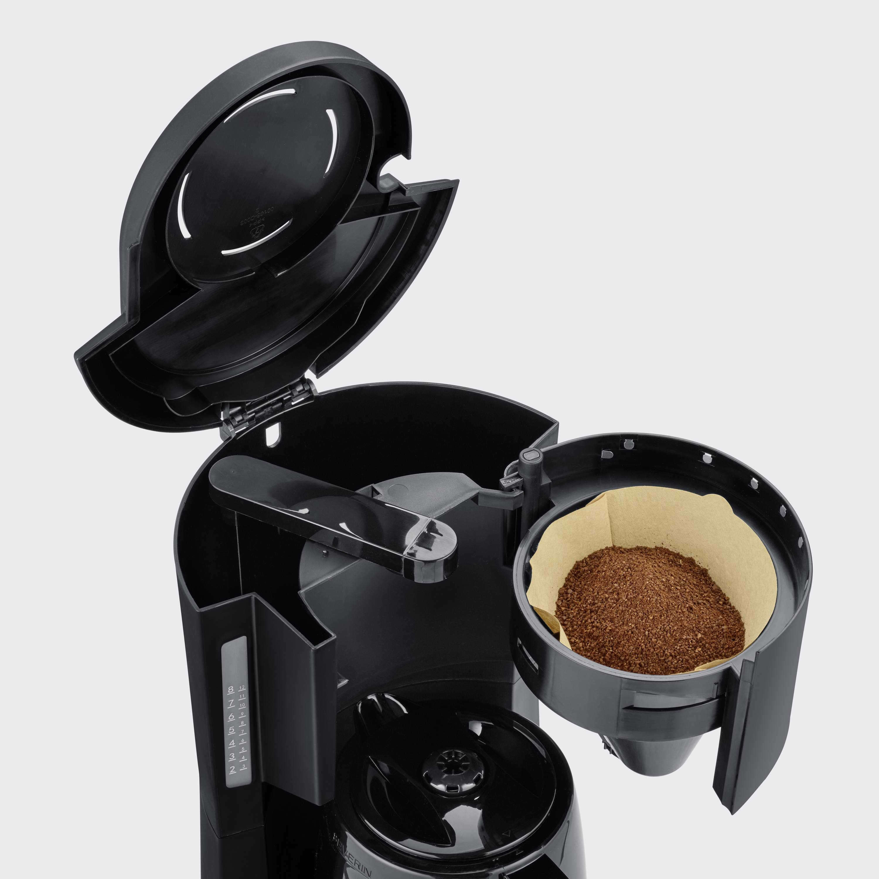 An opened coffee machine reveals the swivel filter holder filled with fresh coffee grounds and the water reservoir.