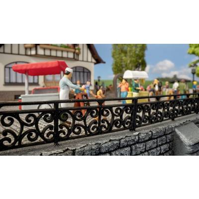 A miniature scene depicts a bustling market scene with an ice cream cart in the foreground. People are standing around market stalls.