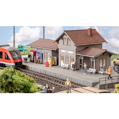 A model railway station with waiting figures, a train at the station, and a sign reading 'Amtszell'.