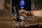 A hand adjusts the settings of a black microphone positioned in front of an open laptop on a wooden table.