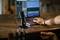A microphone on a table in front of a laptop displays an audio programme. A person is editing sound files and playing guitar.