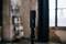 A black microphone stands in a room with an industrial design. A shelf and a window are visible in the background.