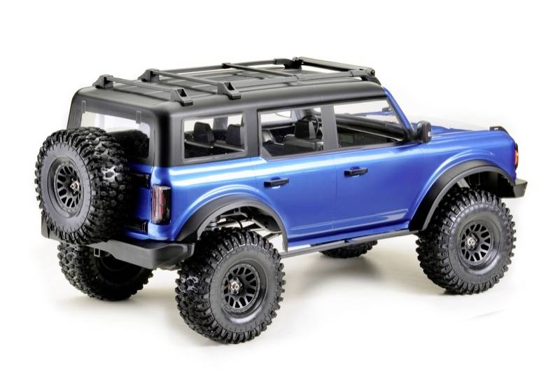 A blue off-road vehicle with large tyres and a spare wheel at the rear, photographed from behind.