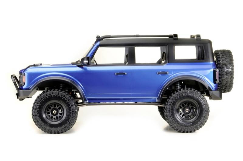 Blue toy off-road vehicle in side profile against a white background, with a large black tyre and plastic roof.