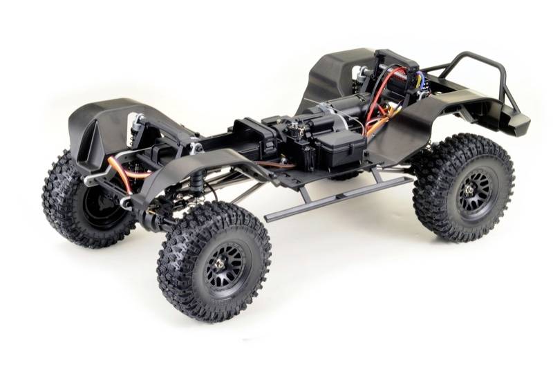 Remote-controlled car chassis with exposed frame and large, robust tyres. Electronic components and cables visible.